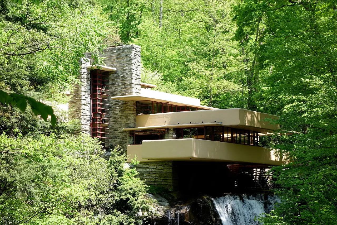 Cantilevered terraces of a house among trees above a stream