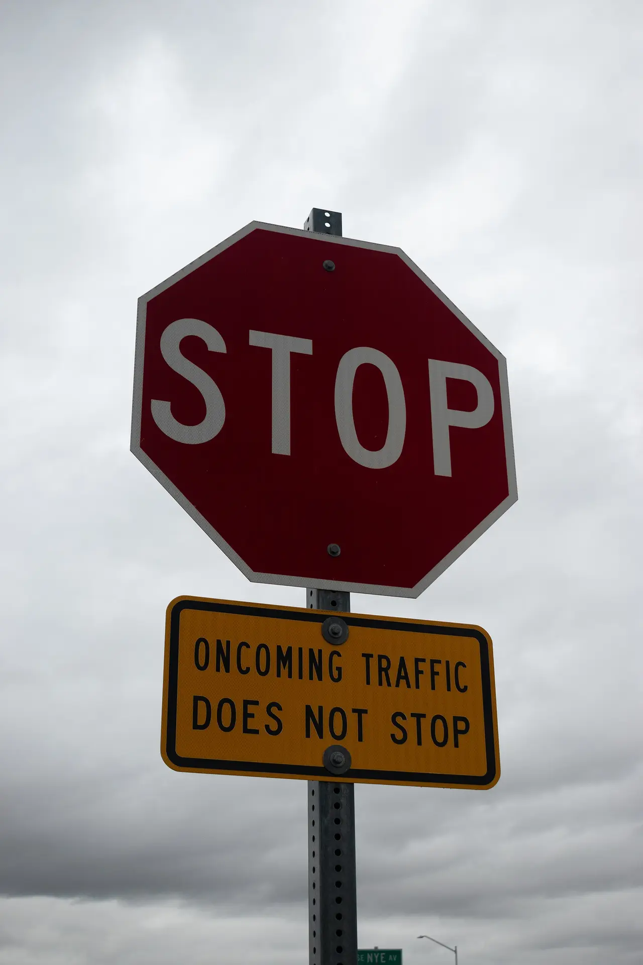 A red stop sign above an orange oncoming traffic warning sign