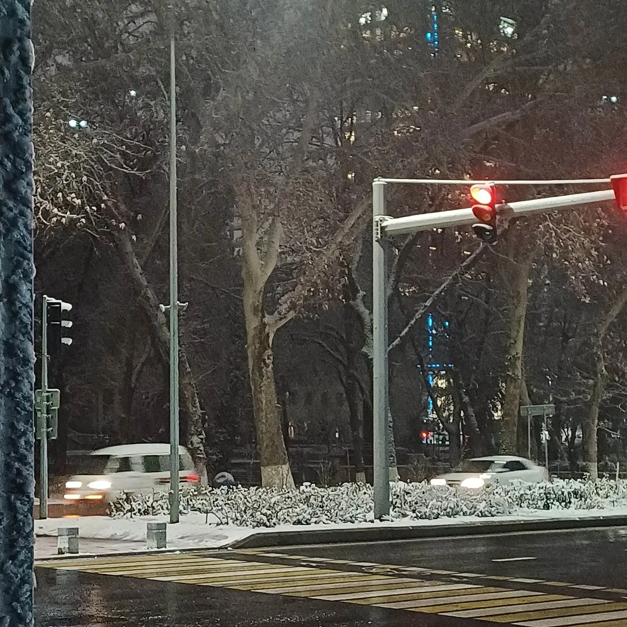 A red traffic light above a street in falling snow