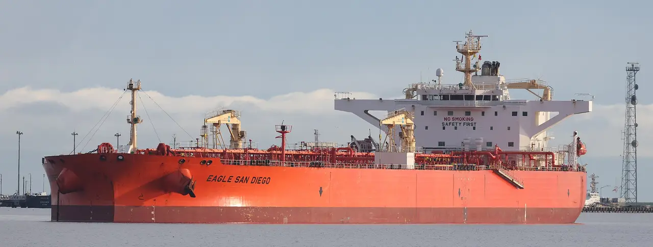 A red-hulled oil tanker on calm water