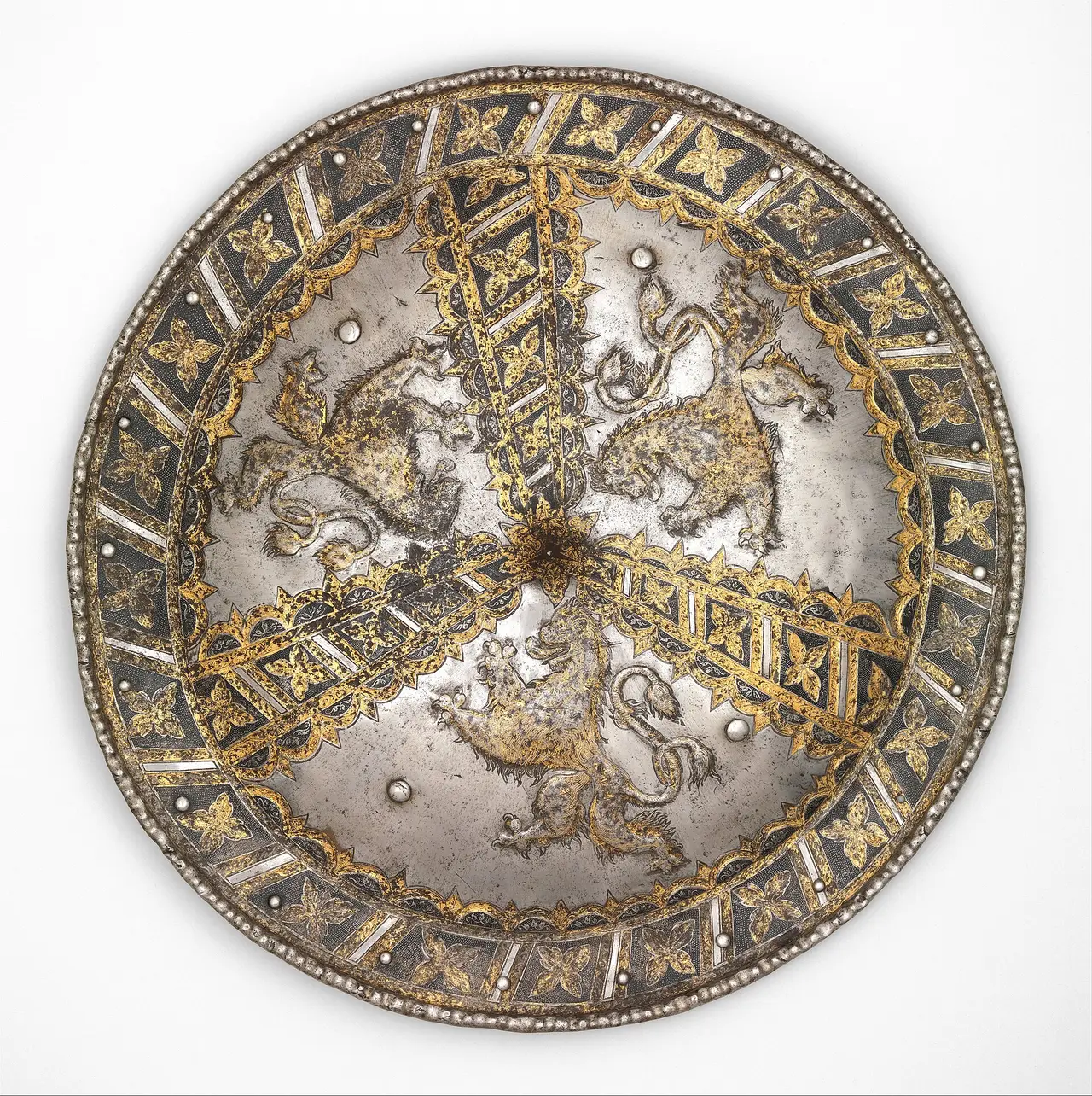 A round steel shield with gold decoration on white