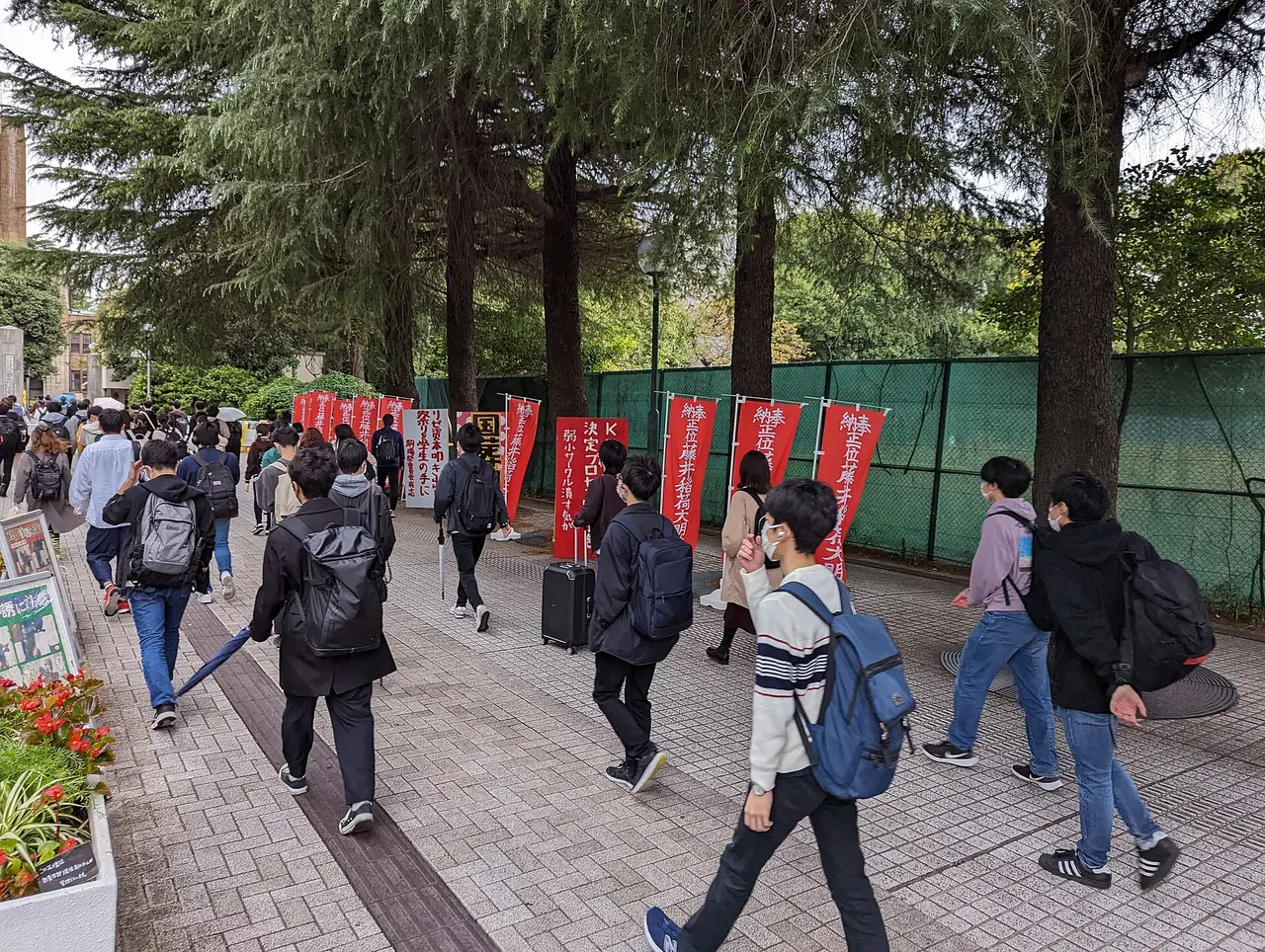 Students with backpacks walking along a tree-lined path