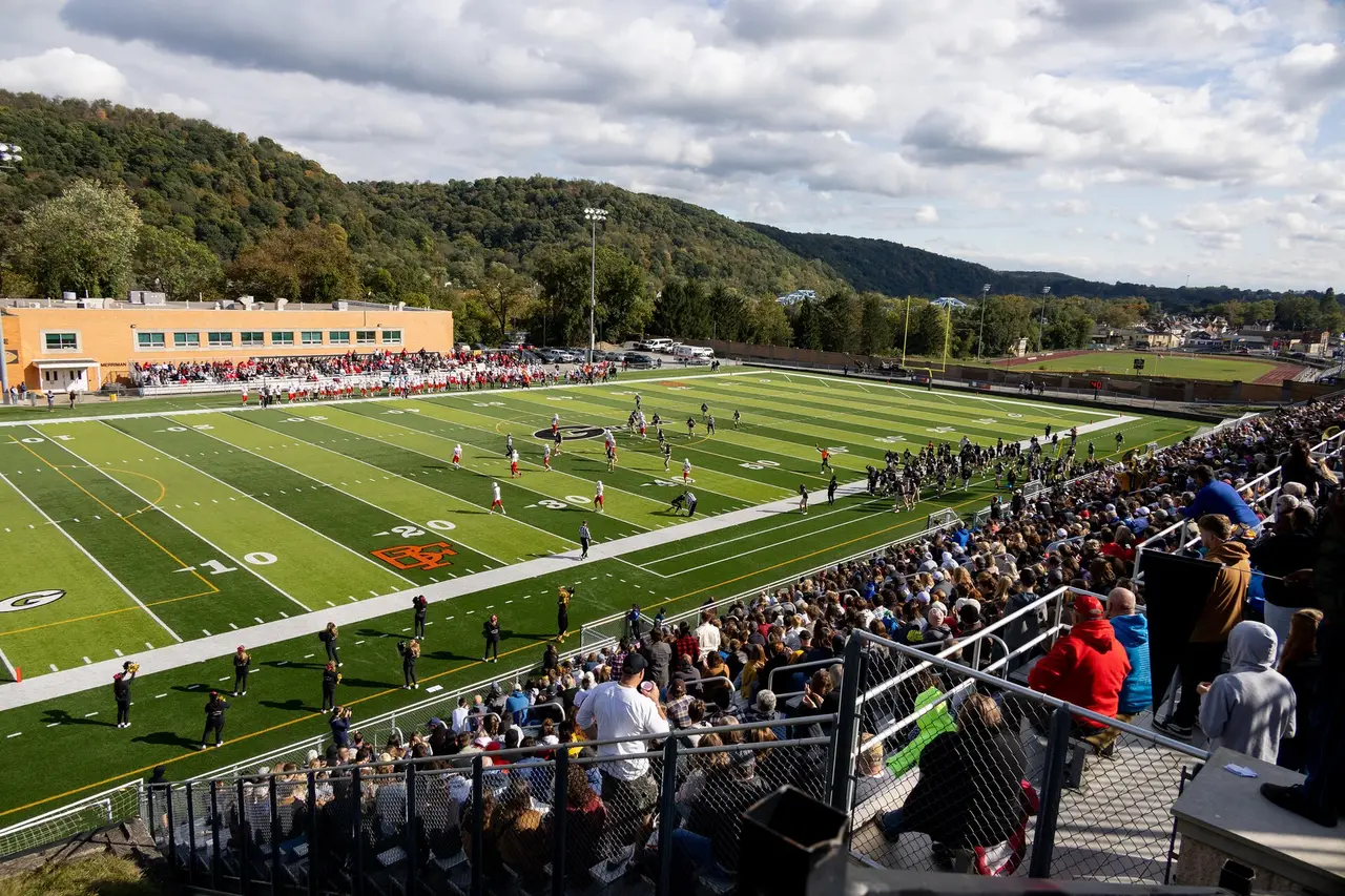 Crowd in the stands watching an American football game on a green field