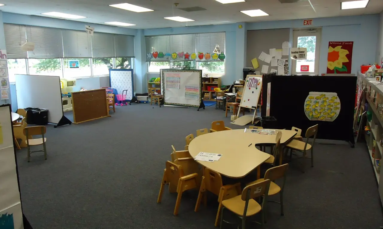 A bright preschool classroom with small chairs and a curved table
