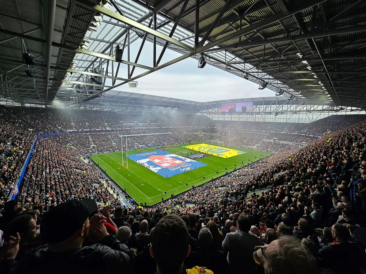 A crowded stadium viewed from inside with a green pitch