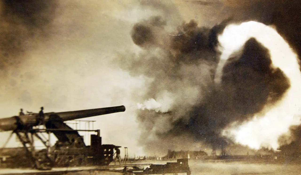 Sepia photograph of a large gun firing with a cloud of smoke