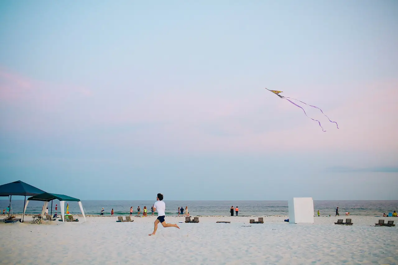 A kite in the sky over a sandy beach with people
