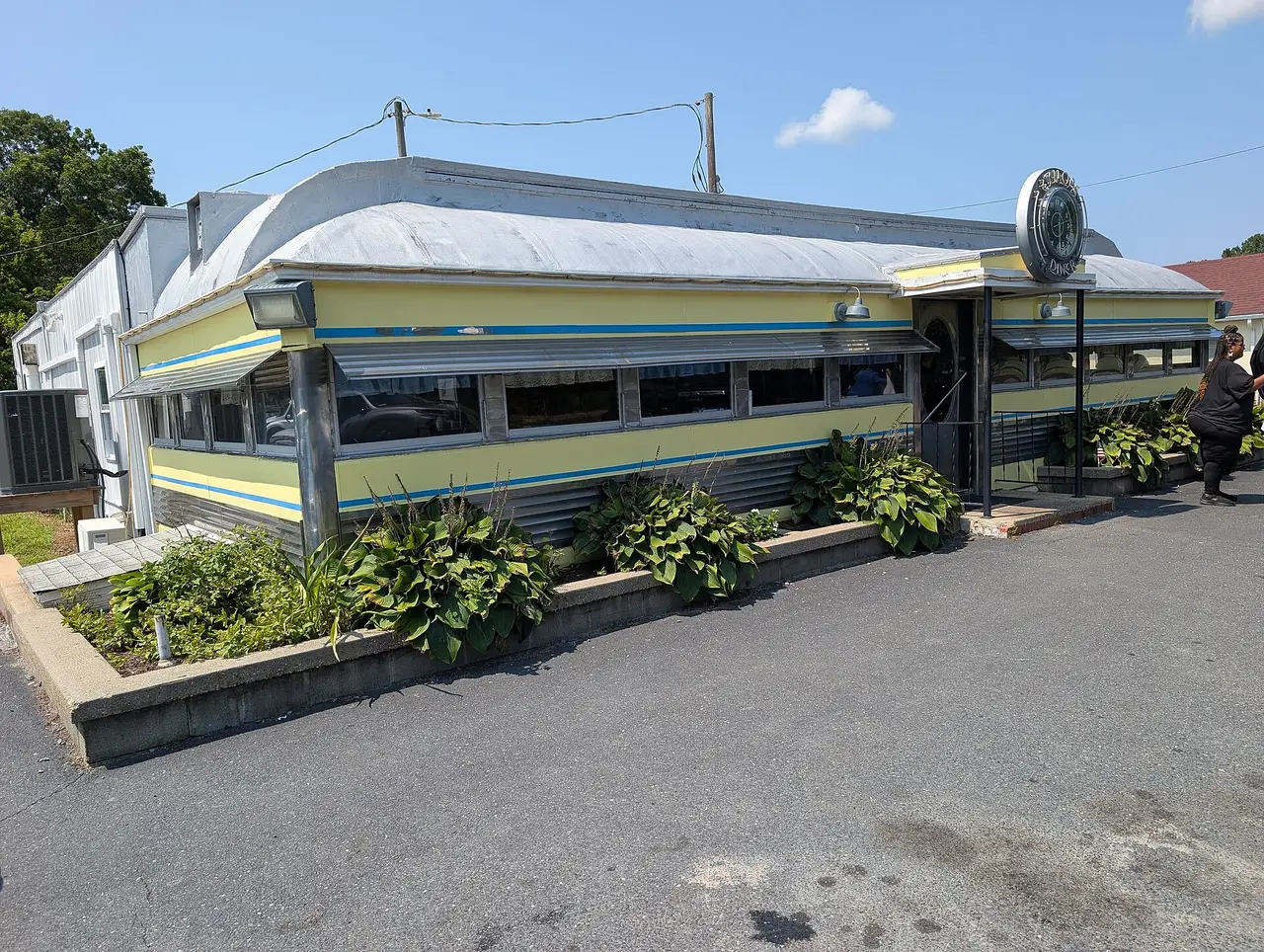 Curved-roof American diner with green and cream bands and a car park