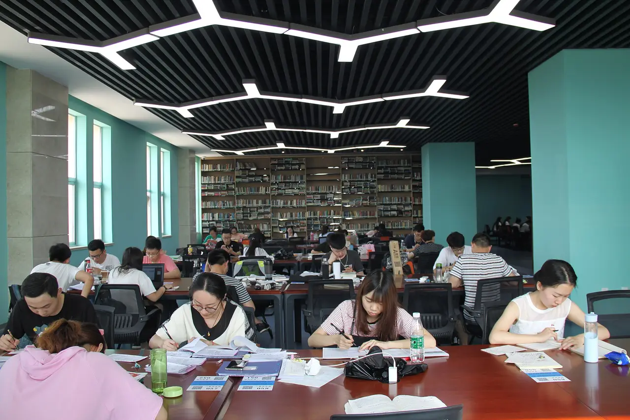 Students studying at long tables in a bright university library