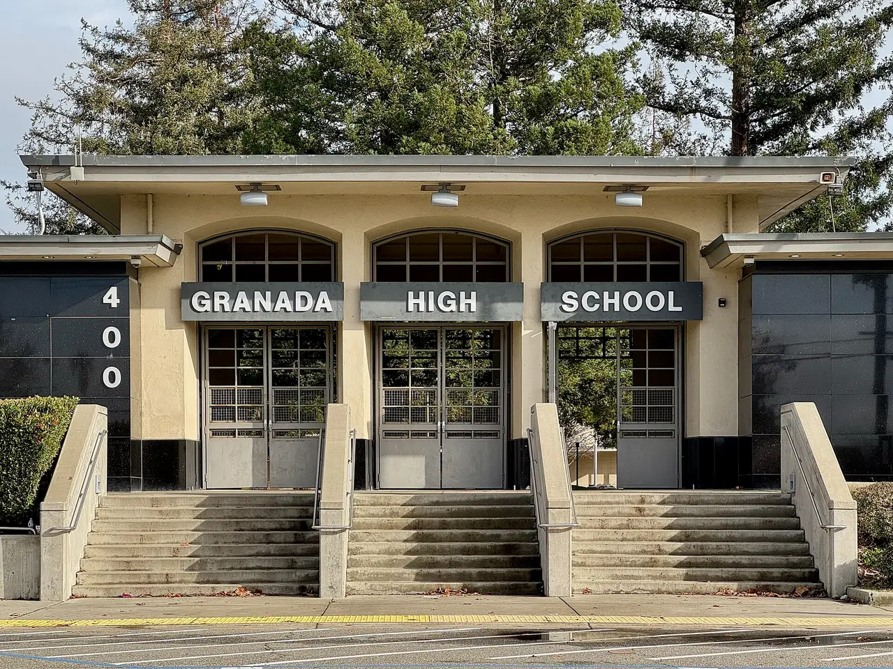 Front steps and doors of a high school under a sign reading Granada High School