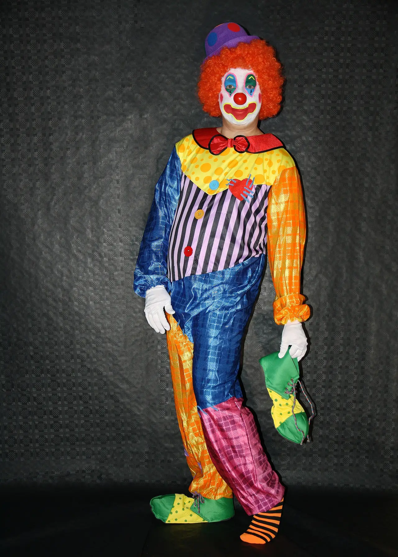 A colourful clown costume with an orange wig on display
