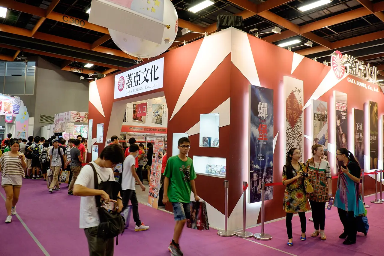 Visitors walking past a red publisher's booth at a comics exhibition