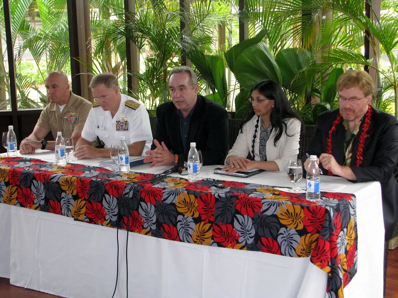 Five people seated at a table with water bottles at a press conference