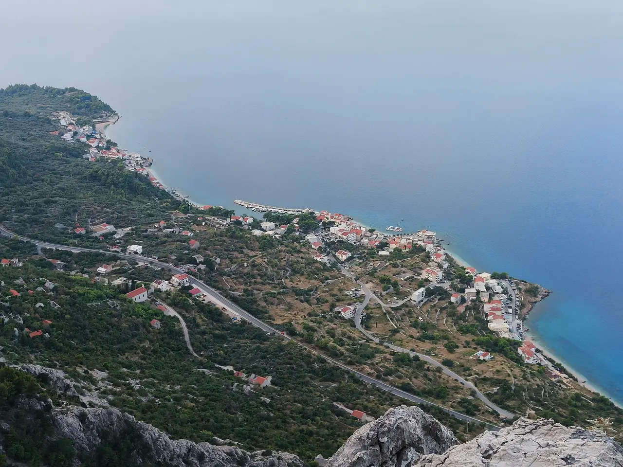 Coastal village and winding road below a mountain beside the sea