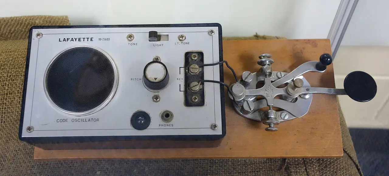 A Morse code key beside a grey code oscillator box on a wooden board