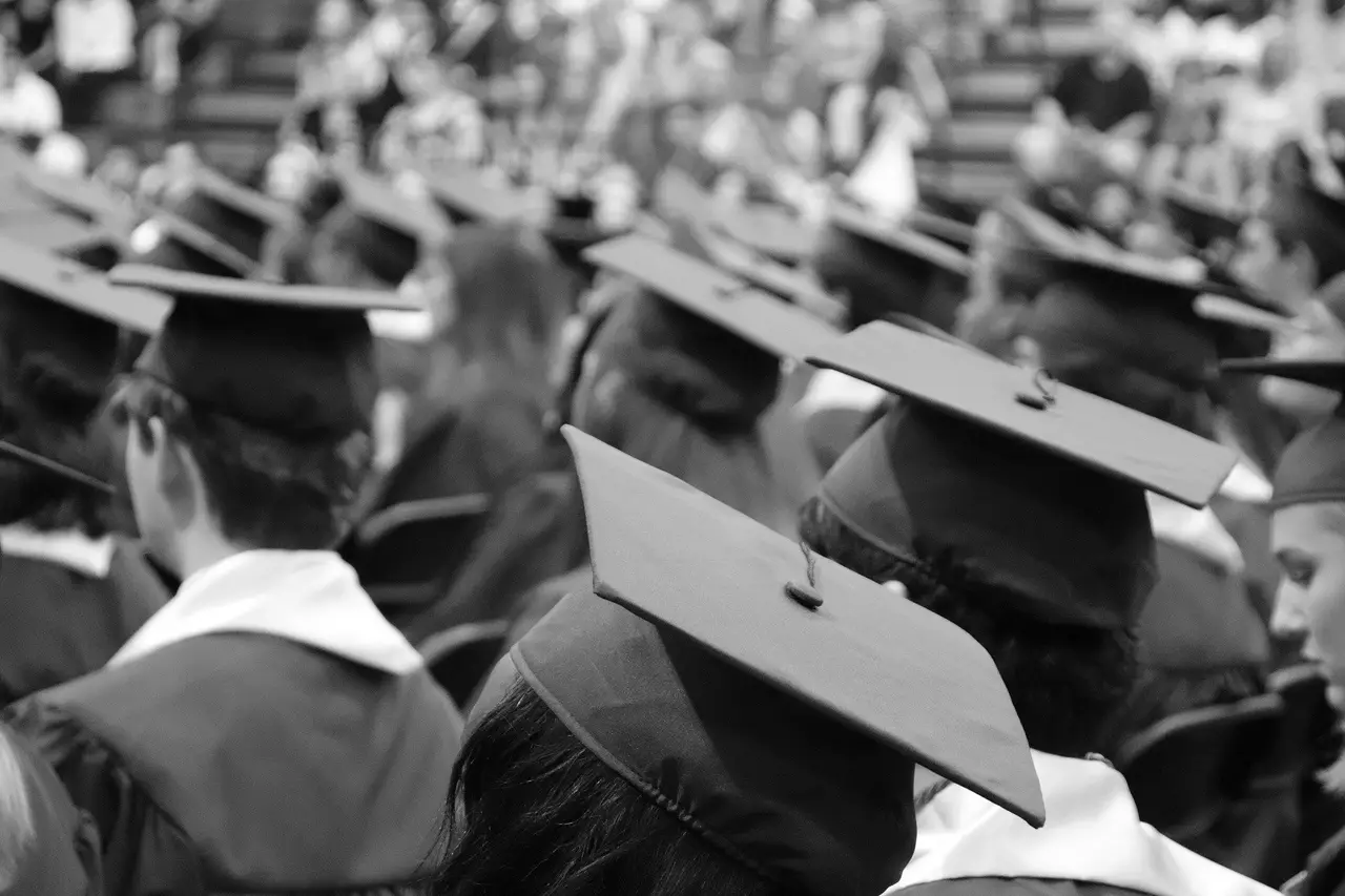 Black and white view of graduates in caps and gowns from behind