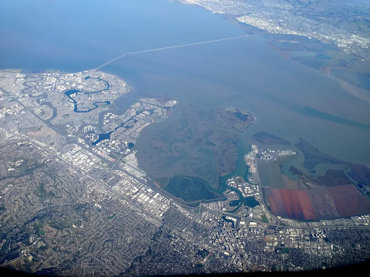 Aerial view of towns beside a bay with a long bridge in the distance