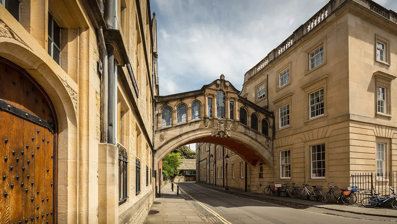 A covered stone bridge between two university buildings over a street