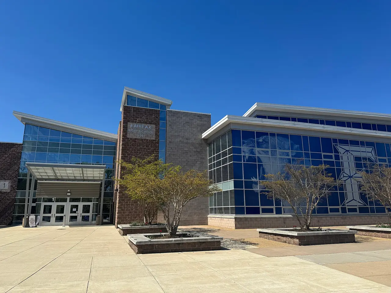 A school building with glass walls and brick under a blue sky