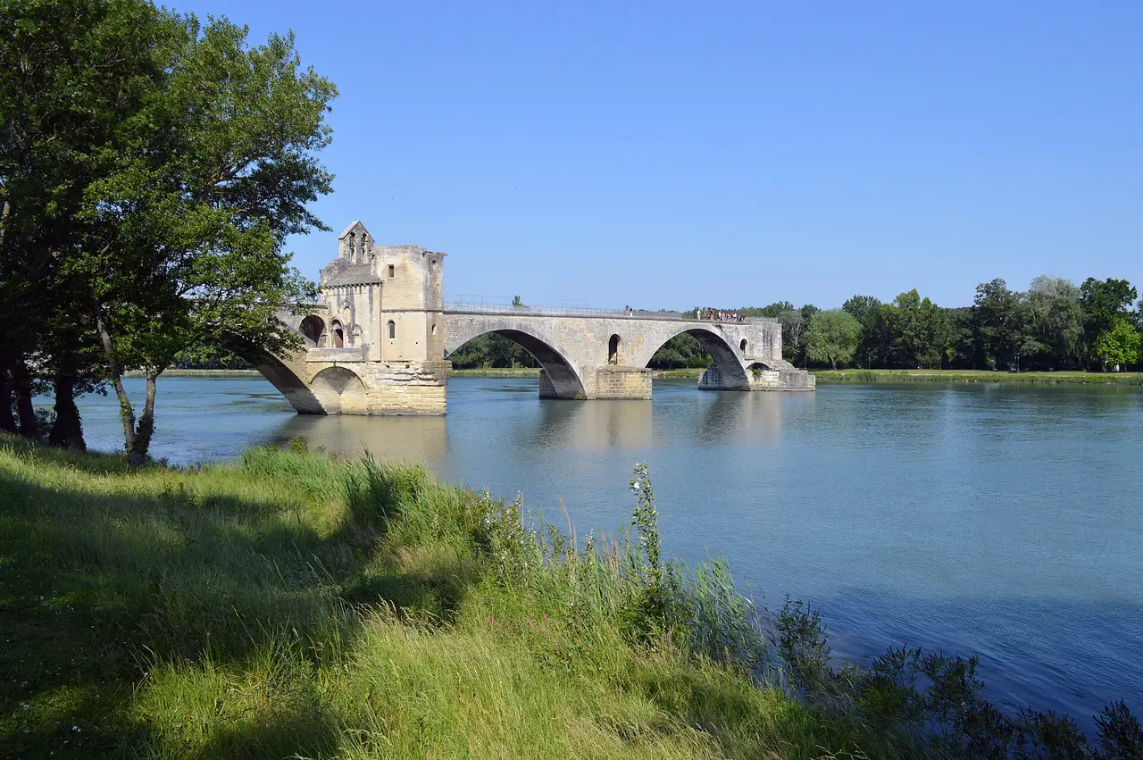 A broken stone bridge with arches over a wide river