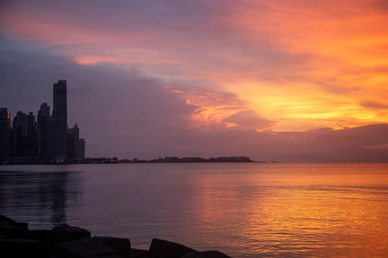 Panama City towers beside the sea under an orange sunset sky