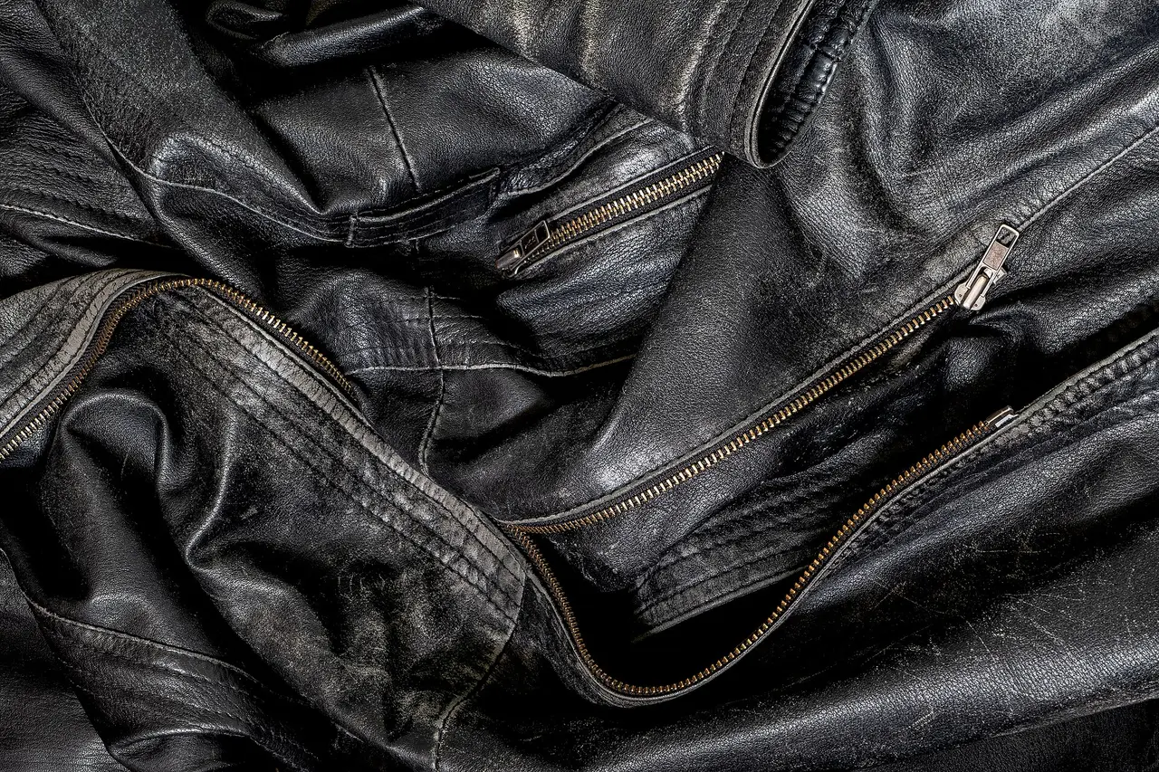Creased black leather with a brass zip and stitched seams