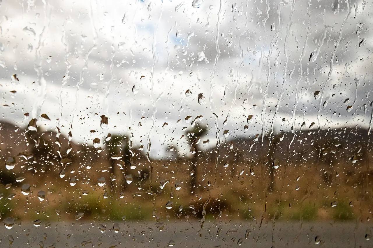 Raindrops on a window with a blurred landscape behind