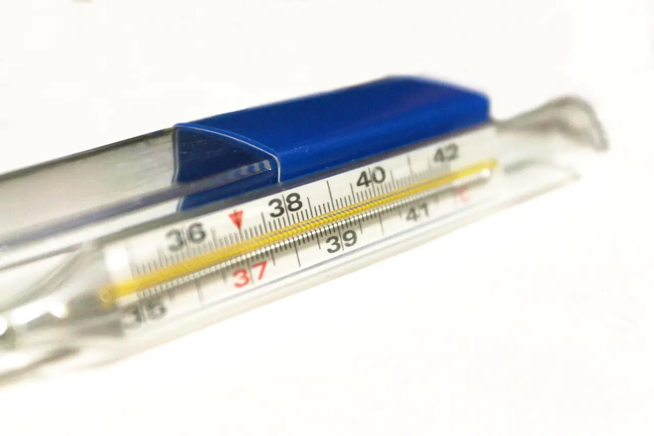 A glass mercury thermometer with a blue cap on white