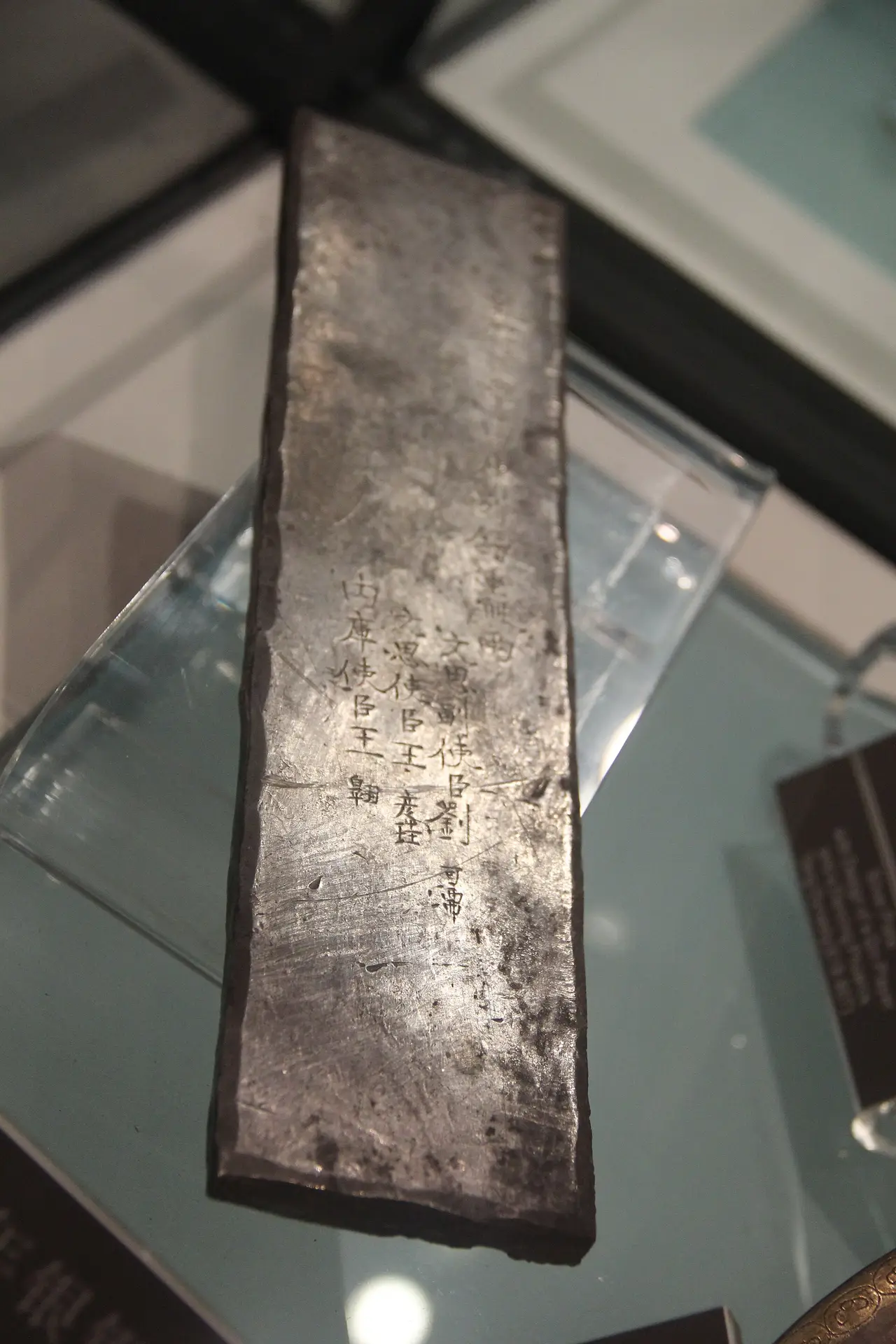 A tarnished rectangular silver bar lying in a museum display case