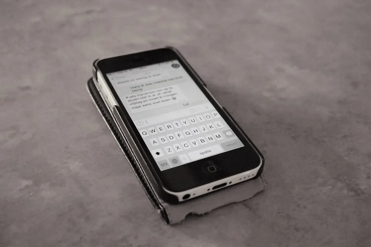 A smartphone on a grey surface showing a list of text messages