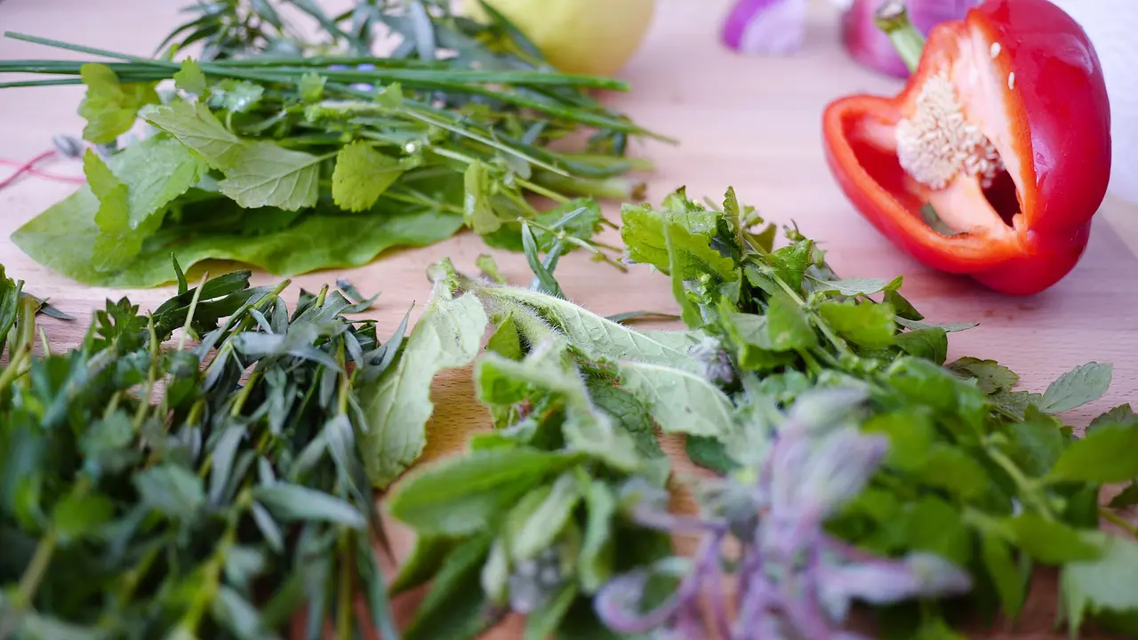 Fresh green herbs next to a halved red pepper