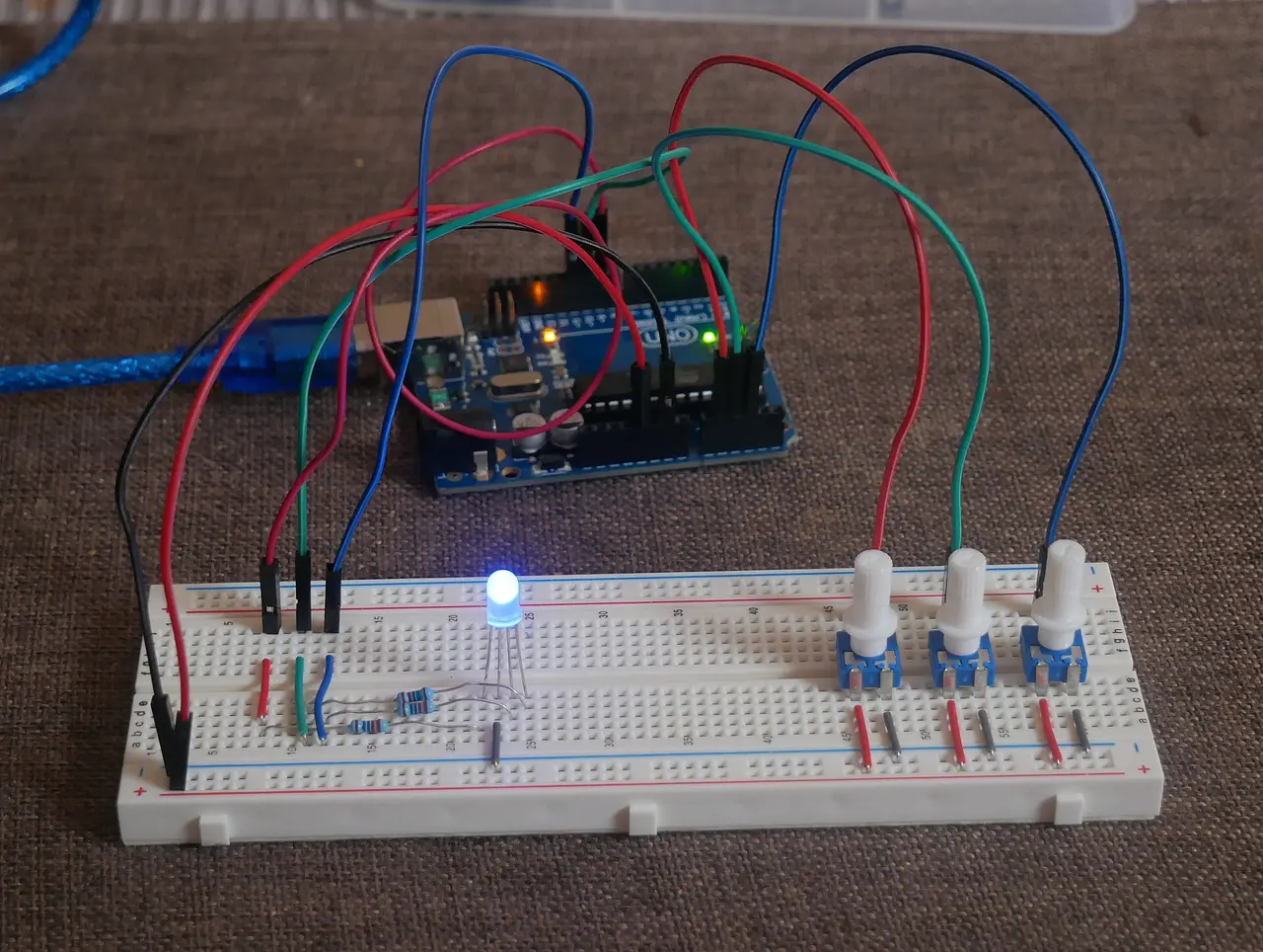 A circuit board linked by coloured wires to a breadboard with a blue LED