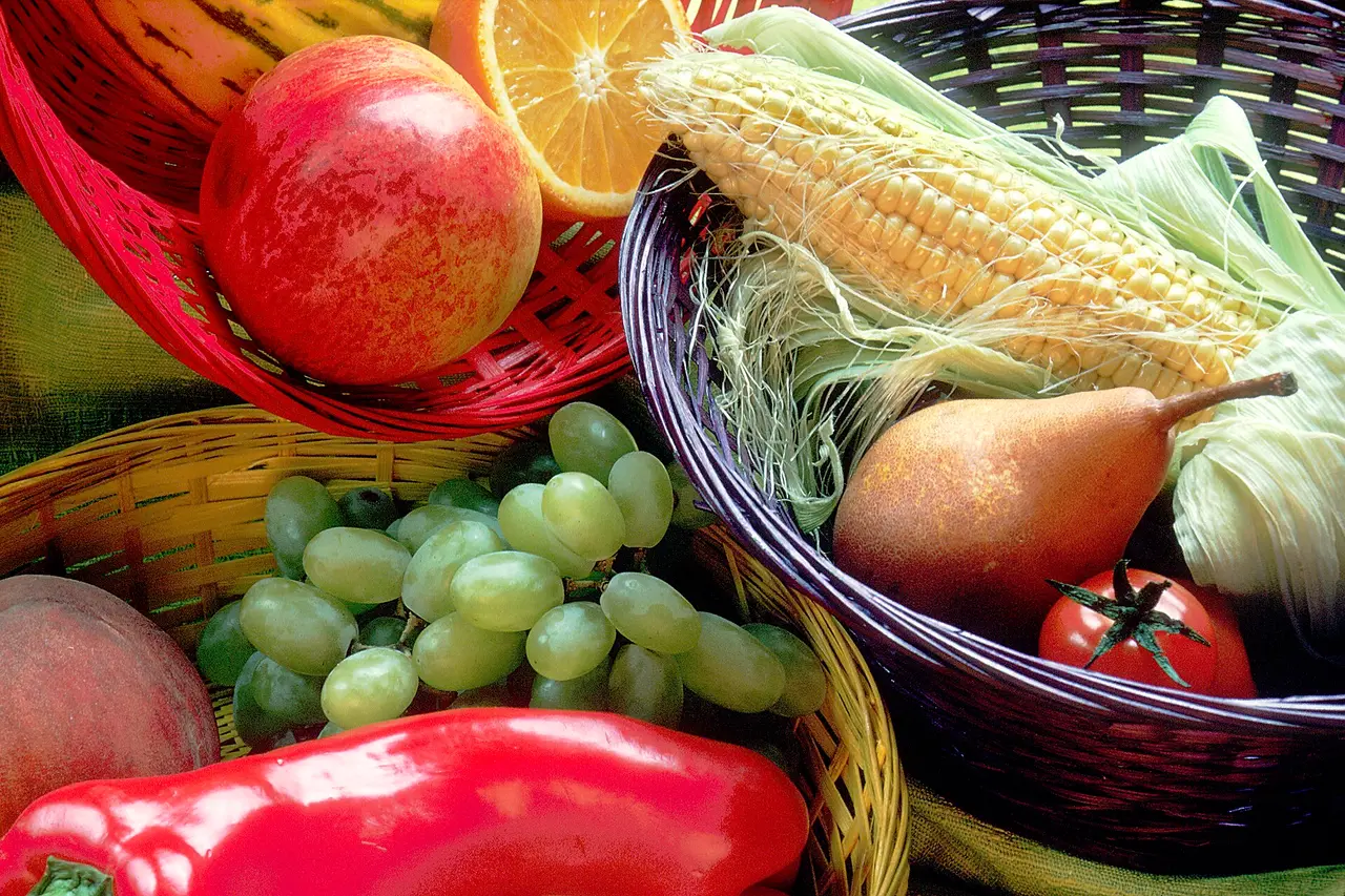 Wicker baskets of fruit and vegetables including grapes, corn and a pear
