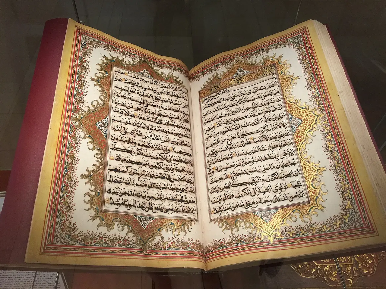 An open illuminated Quran with decorated borders around the Arabic text