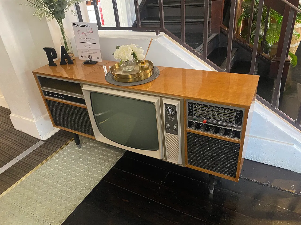 A retro wooden-cased television near a staircase