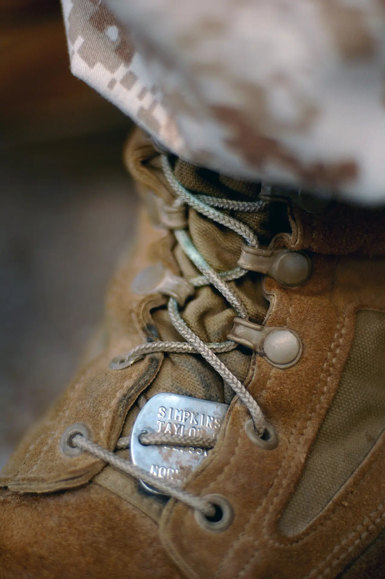 A close-up of a tan boot with tied laces and metal eyelets