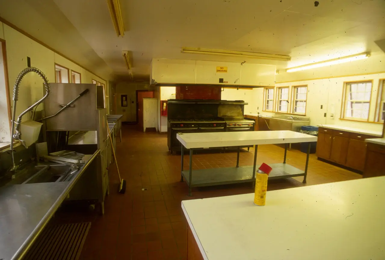 Wide commercial kitchen with steel appliances and white worktops