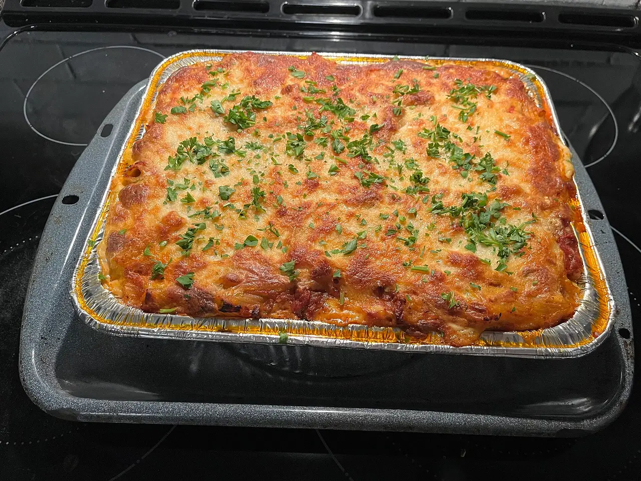 Baked ziti with browned cheese and herbs in a rectangular tray
