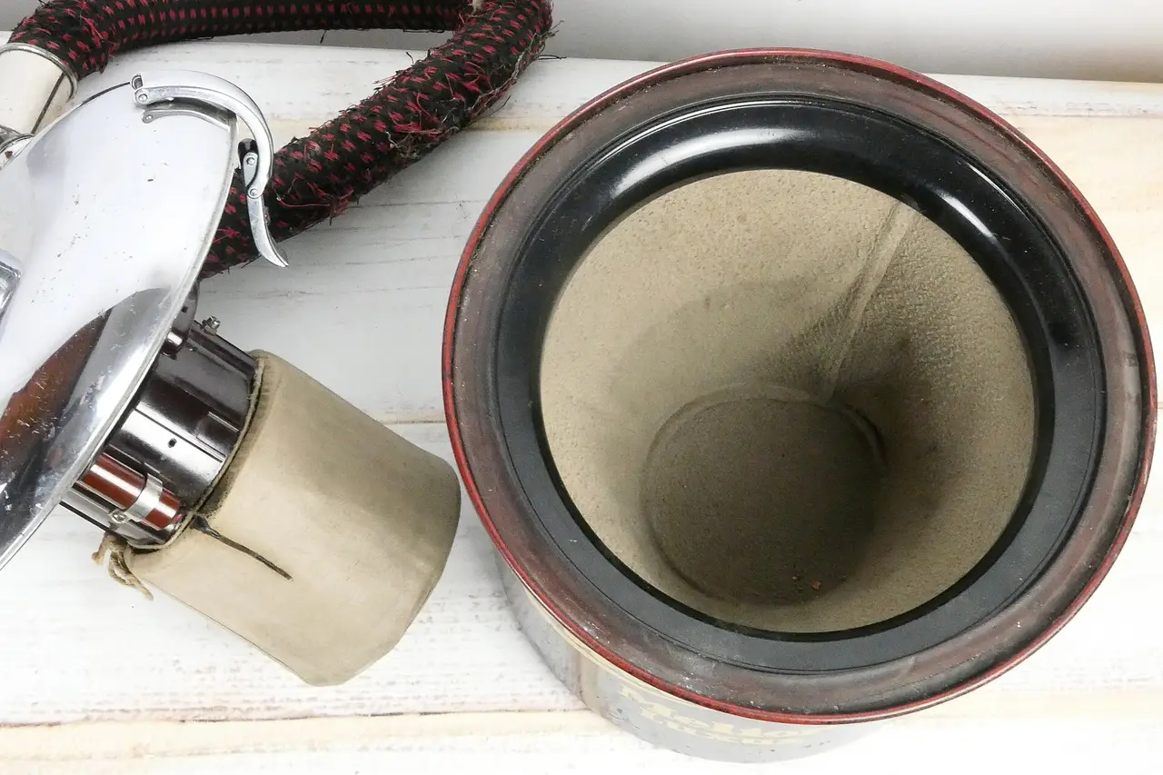 A round vacuum cleaner filter and motor housing on a white wooden table
