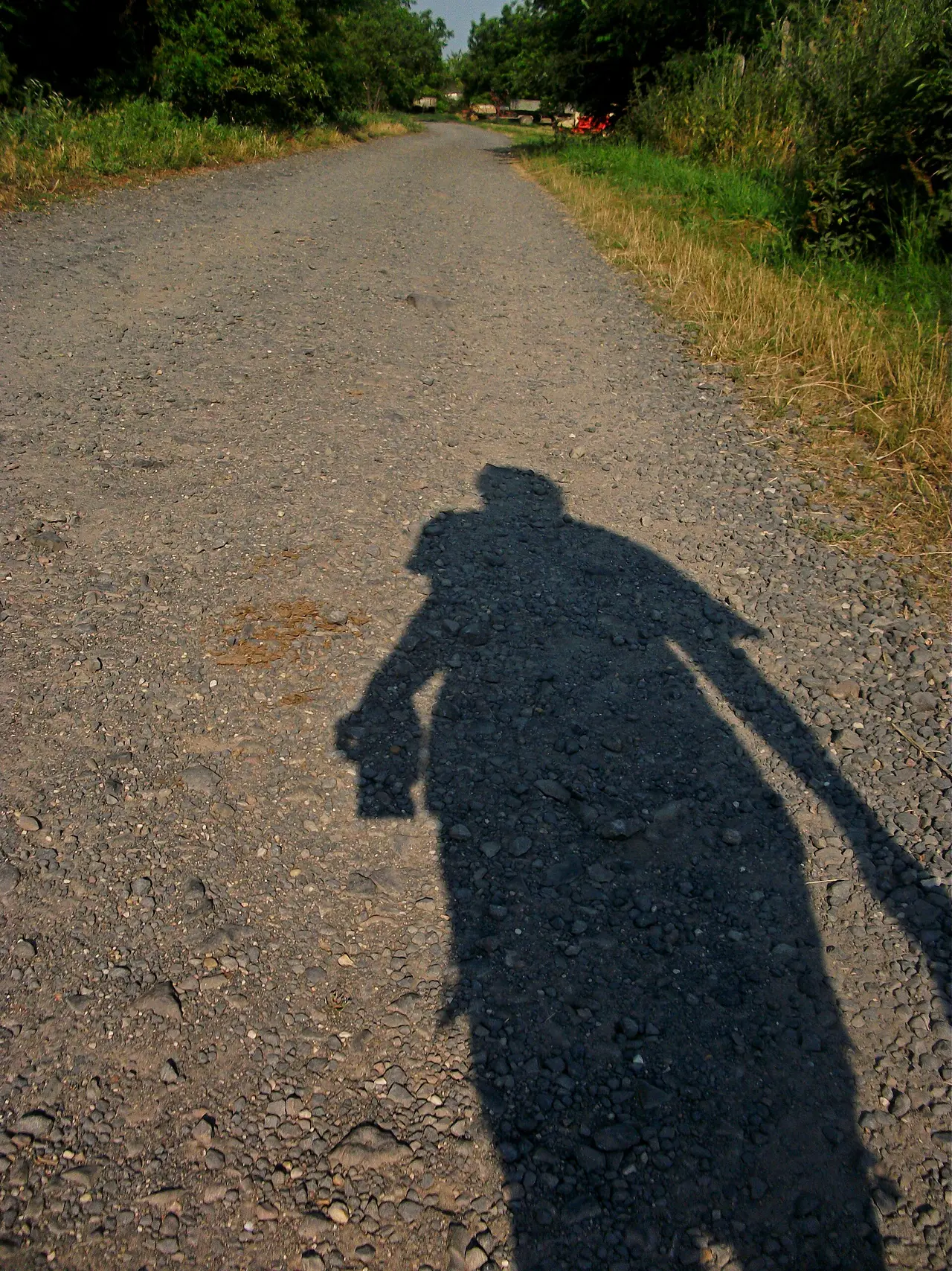 A person's shadow on a gravel track