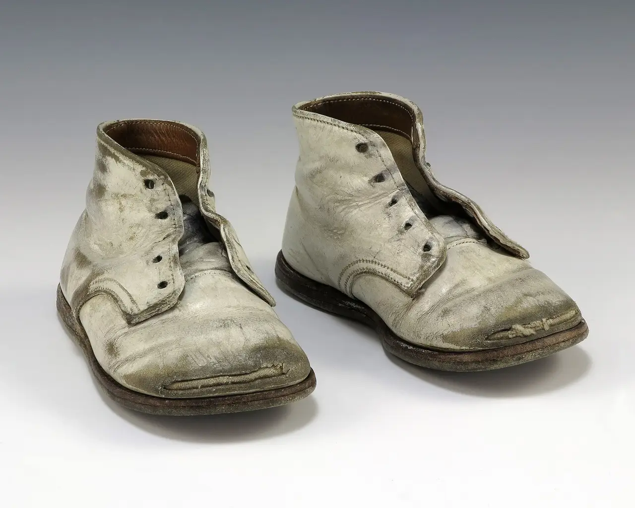 A pair of worn white lace-up baby shoes