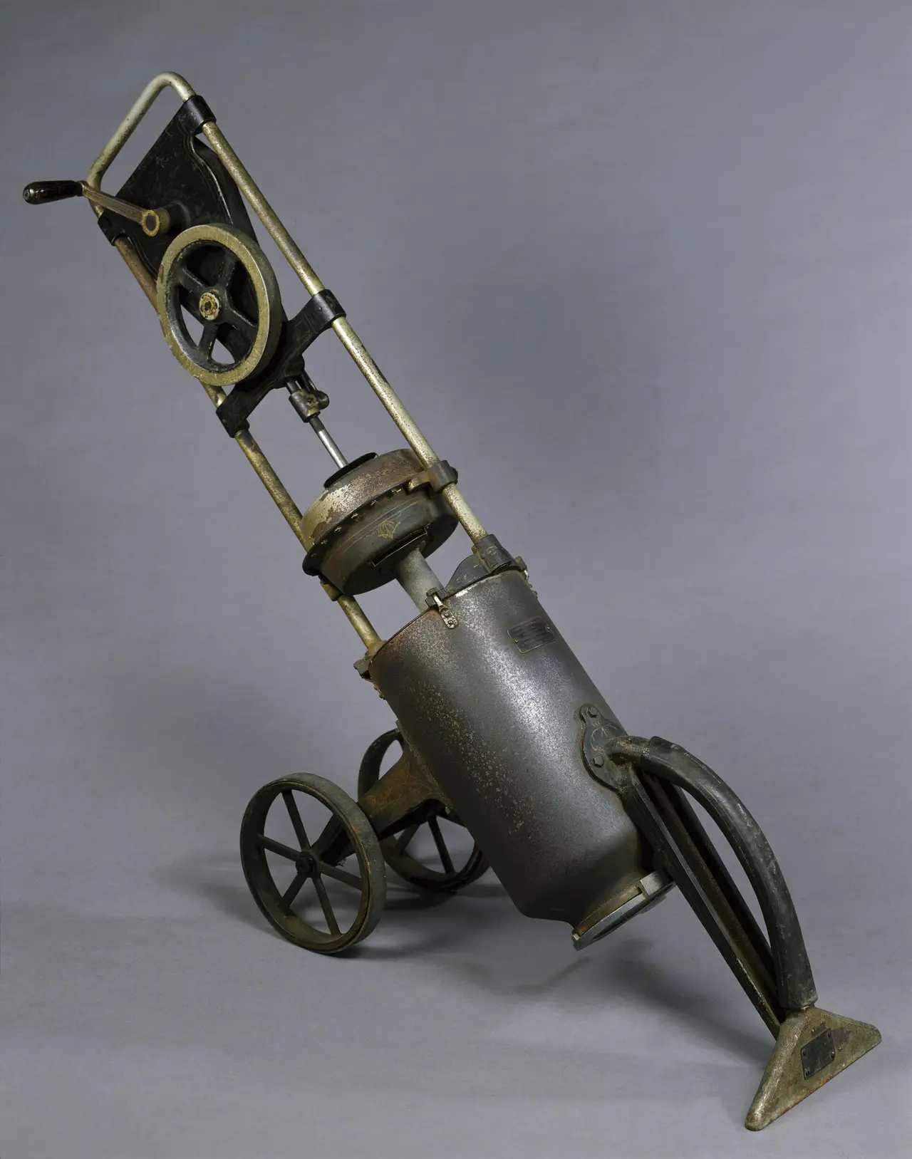 An old metal cylinder vacuum cleaner on small wheels
