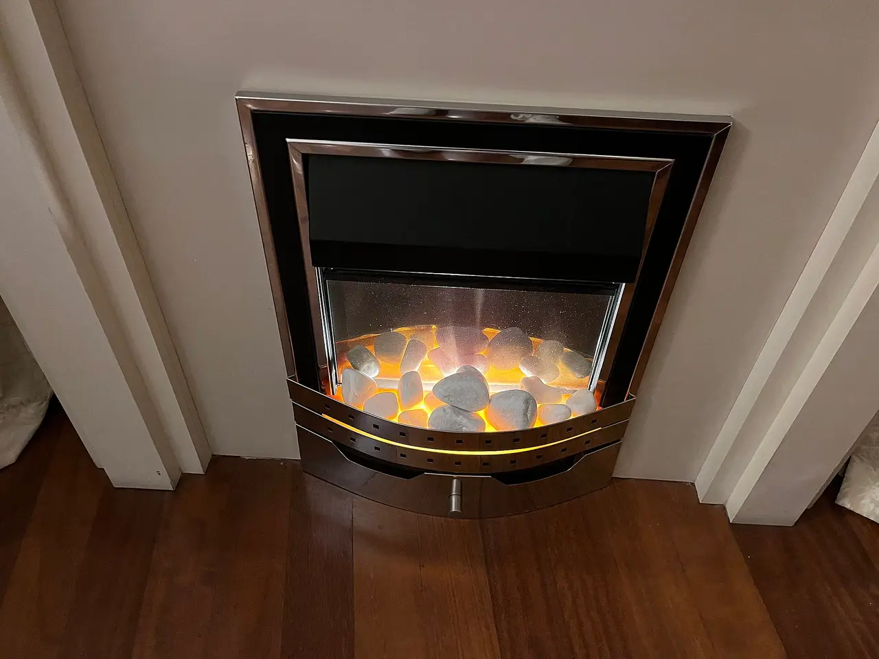 Electric fireplace with lit stones in a white surround