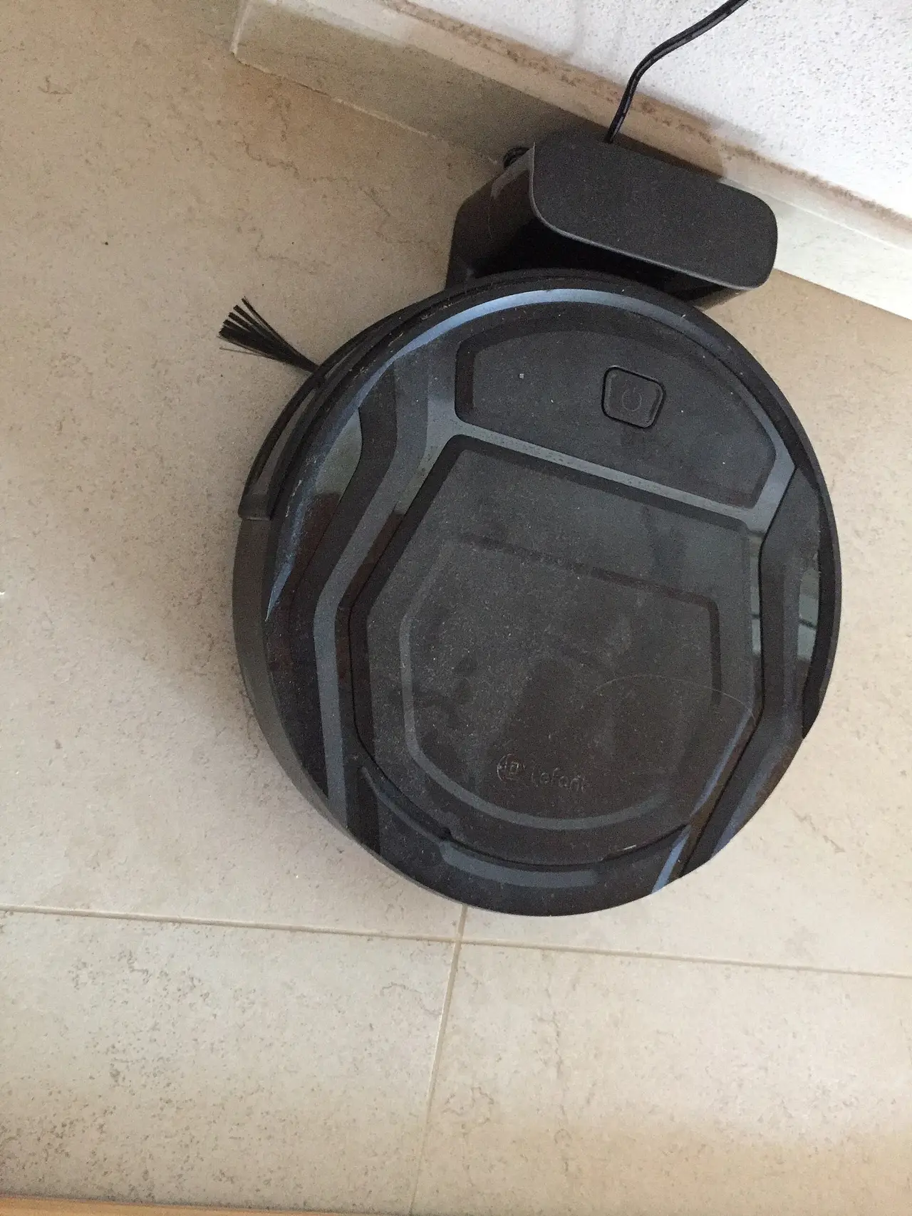 Round black robot vacuum cleaner on a pale floor
