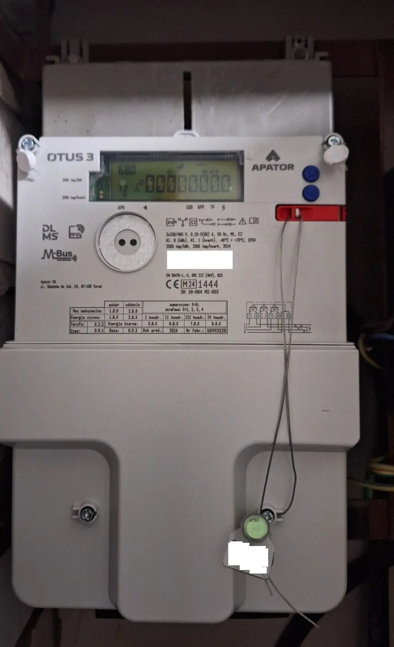 Grey electronic electricity meter with a digital display on a wall