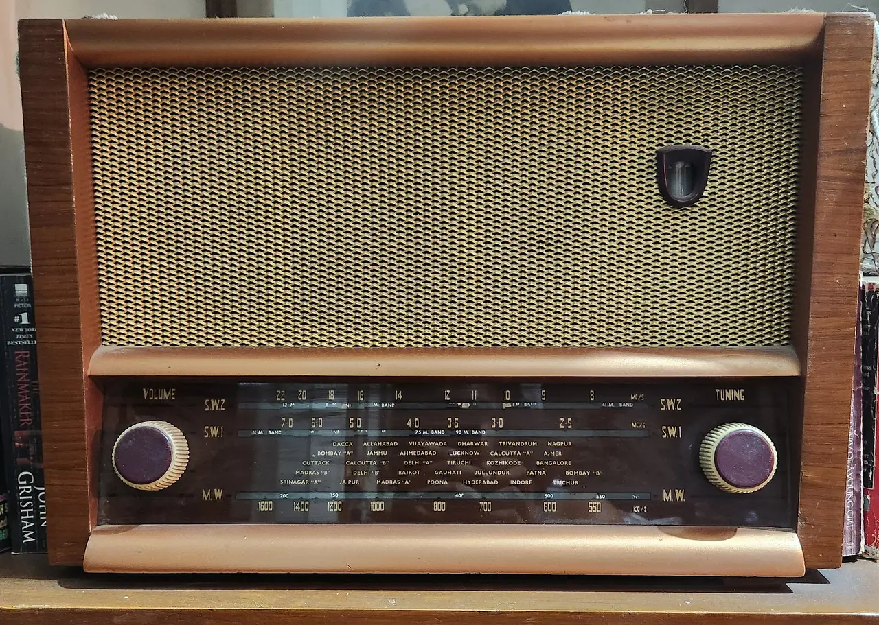 A wooden radio with a speaker grille and two knobs