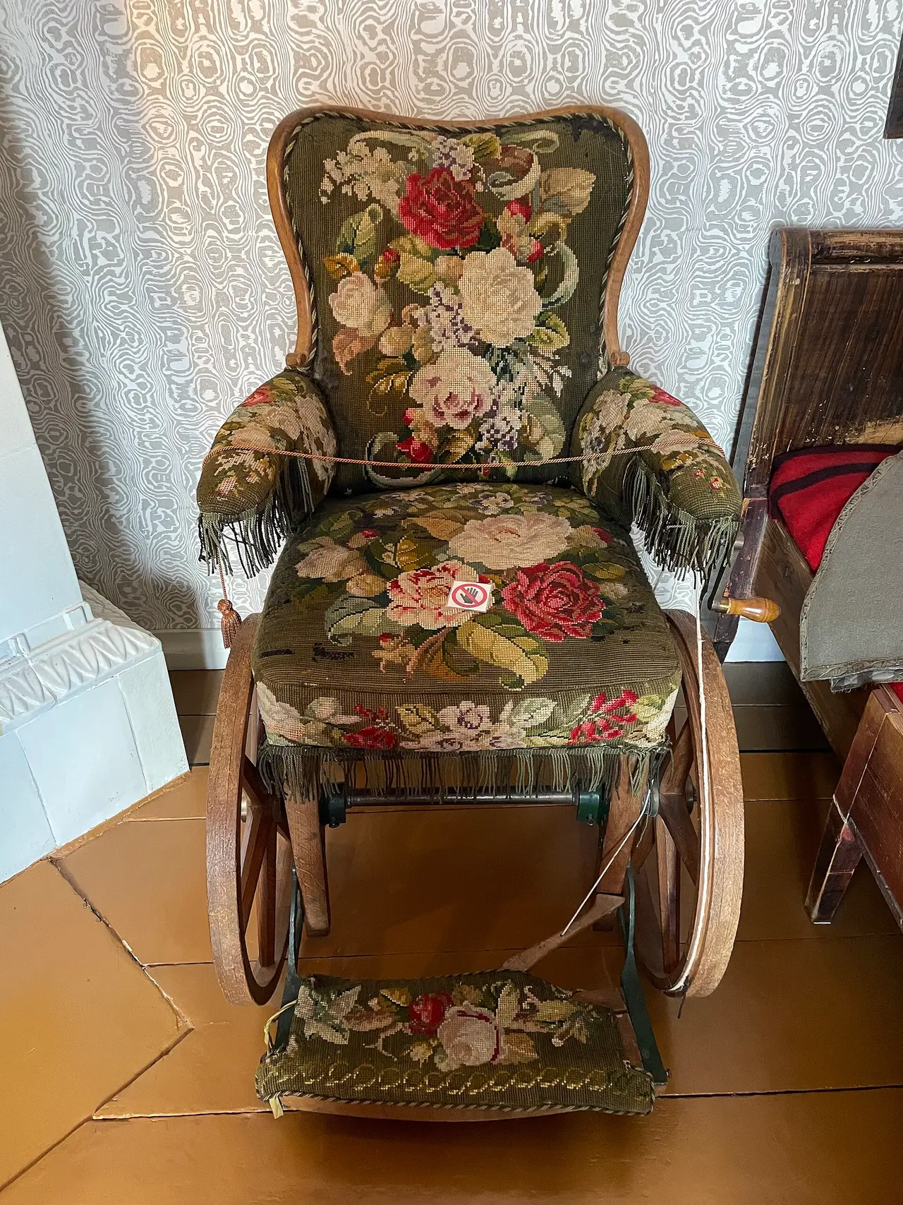 Old wheelchair with floral seat and back on a museum floor