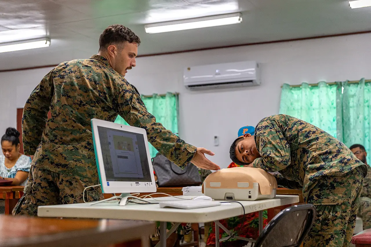 Two servicemen practising CPR on a training manikin in a classroom
