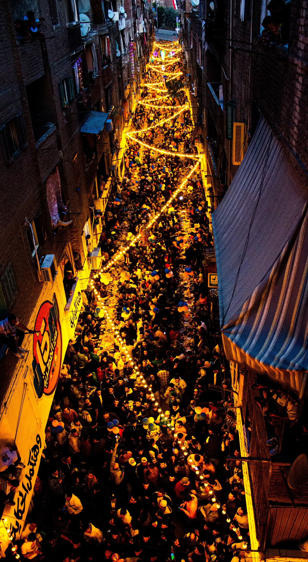 Aerial view of a lit street crowded with people sharing a meal