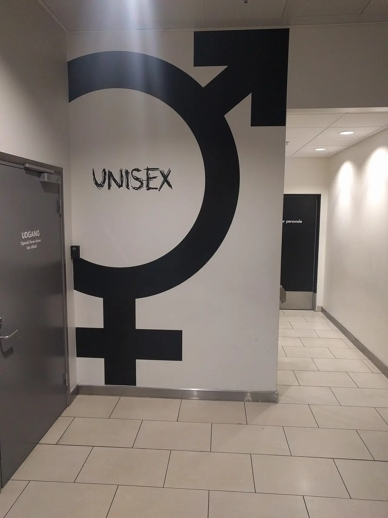 Large black gender symbol with UNISEX on a corridor wall